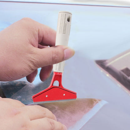 Car window film scraper tool with red metal blade and white comb handle, held by hand
