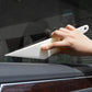 Hand holding white tint squeegee scraper tool on car window film
