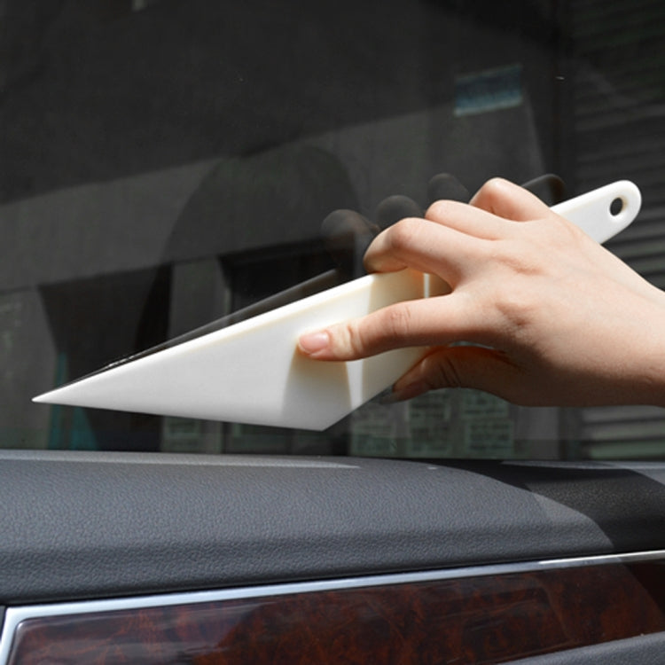 Hand holding white tint squeegee scraper tool on car window film