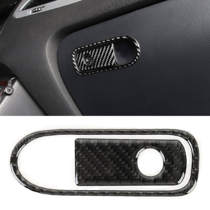 Carbon fiber-pattern armrest switch bezel with oval frame and circular switch opening