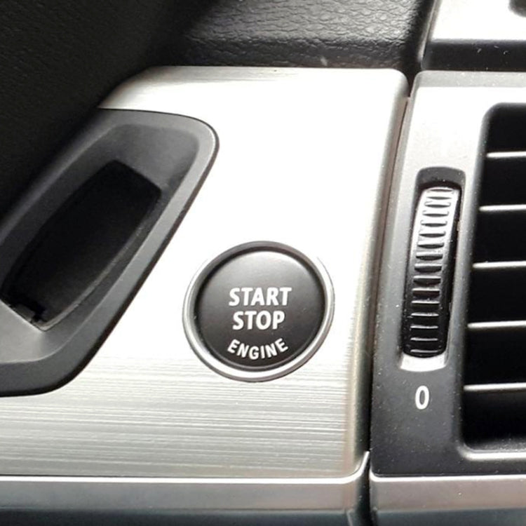 Gray start-stop engine button cover with chrome rim and engraved text