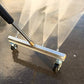 Silver chassis washer bar with four nozzle ports and caster wheels, angled view