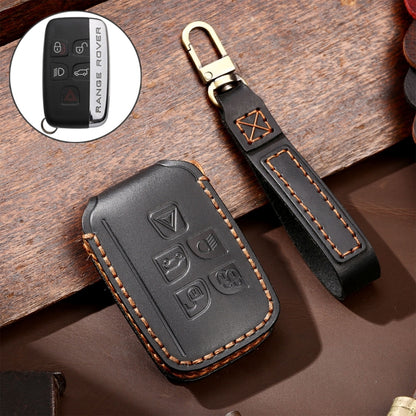 Black leather key fob cover with embossed symbols and stitched wrist strap, gold clasp