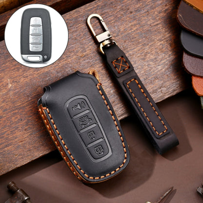 Black leather key fob cover with orange stitching, metal key ring, embossed button icons.