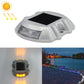 Solar road stud light with amber LED glow, clear lens housing, horseshoe shape.