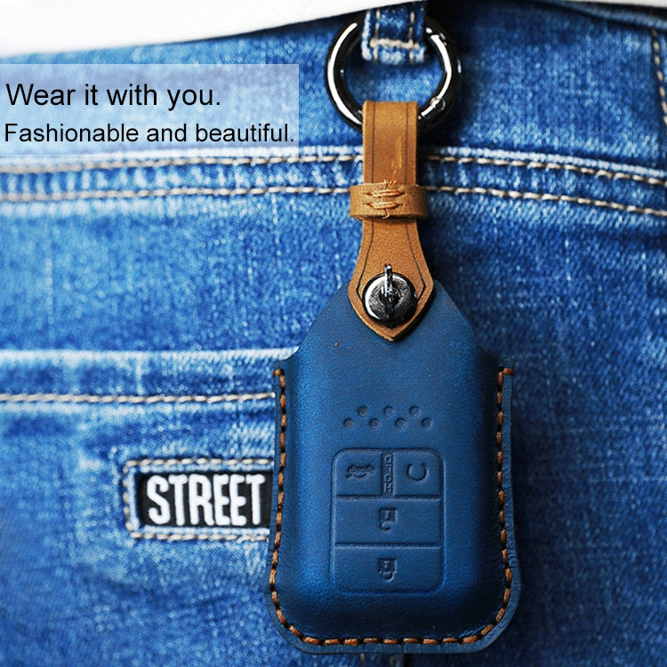 Blue cowhide leather key fob cover with key ring clipped to denim, embossed button icons