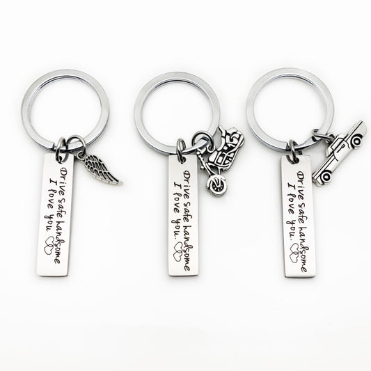 Three stainless steel keychains with round rings and hanging charms beside engraved bars