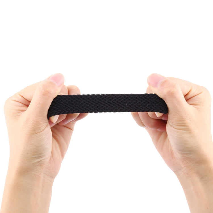 Woven nylon watch band, dark charcoal black, shown being flexed by hands.