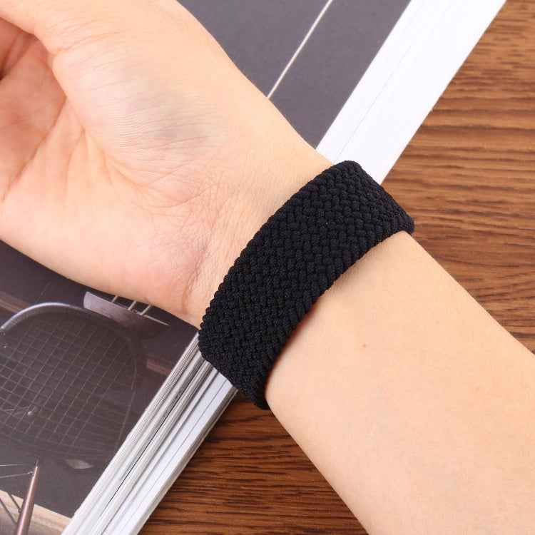 Woven nylon watch band worn on wrist, dark charcoal black, thick braided texture.