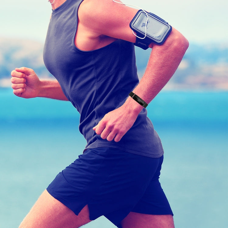 Black milanese watch strap with snap clasp worn on a fitness tracker wrist.