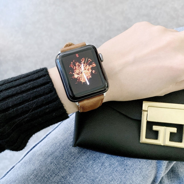 Tan leather watch band with metal buckle on a wrist