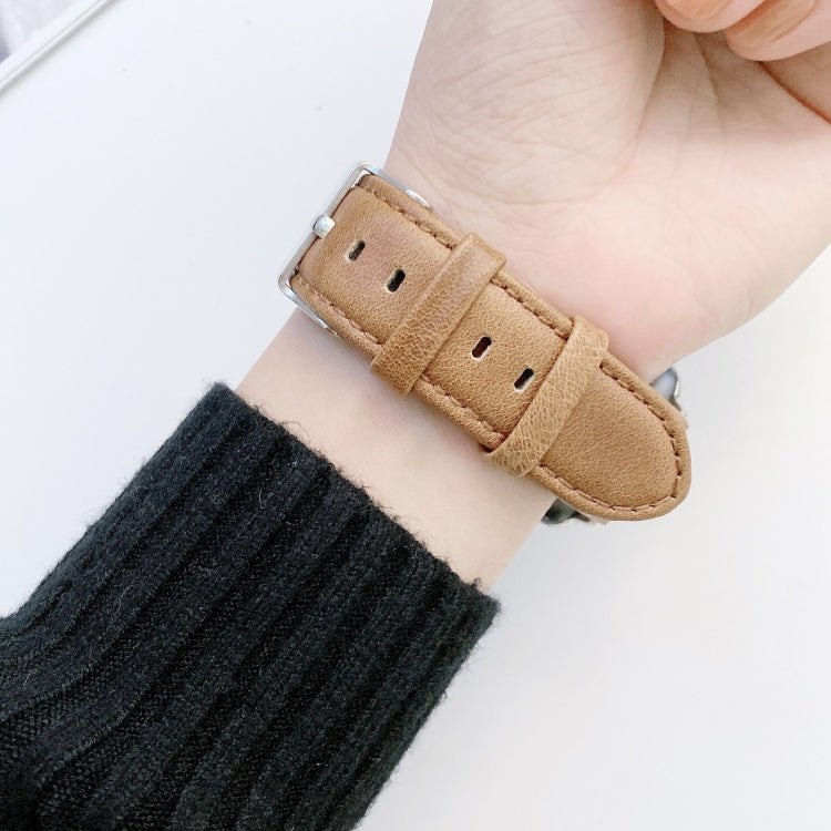 Light brown leather watch band close-up with metal buckle and keeper