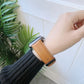 Light tan leather watch band with metal buckle on a wrist