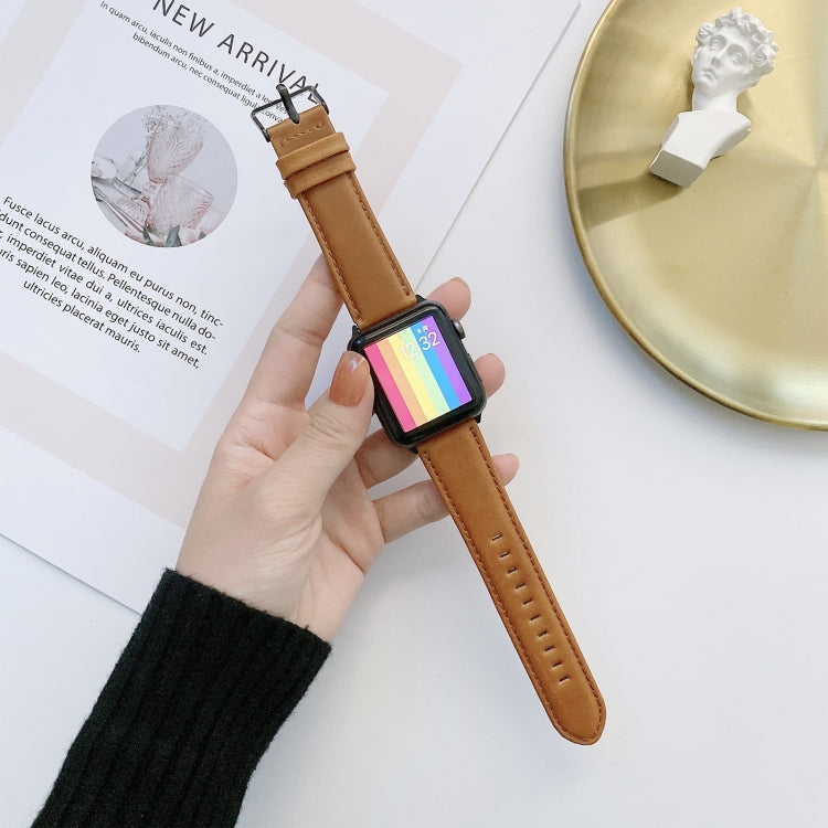 Tan leather watch band with metal buckle, worn on a wrist