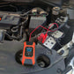 12V battery charger plugged into car battery terminals with red and black clamps