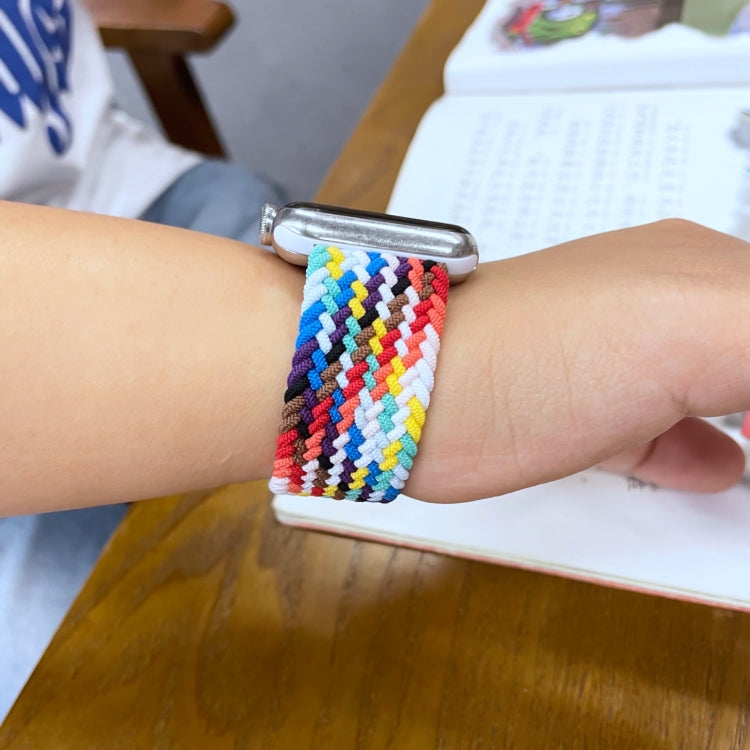 Rainbow braided watchband worn on wrist, secured with metal buckle clasp