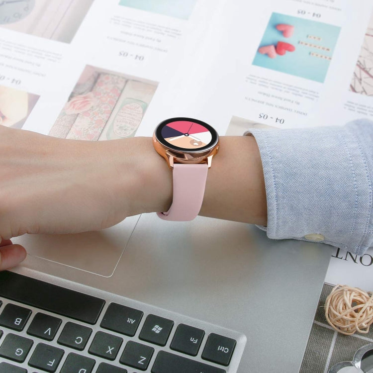 Pink silicone smartwatch strap worn on wrist; metal buckle visible