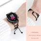 Black heart-link watchband bracelet with beaded tassels, worn with smartwatch.