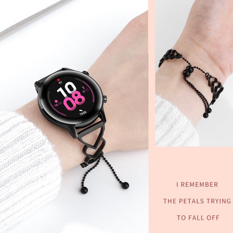 Black heart-link watchband bracelet with beaded tassels, worn with smartwatch.