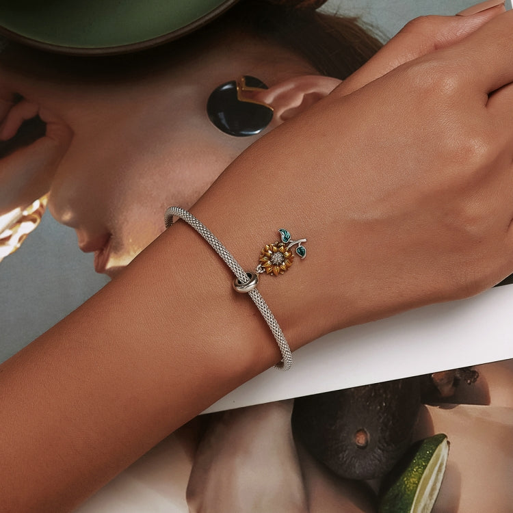 Sunflower charm bracelet on wrist with silver mesh band, yellow flower and green enamel leaves