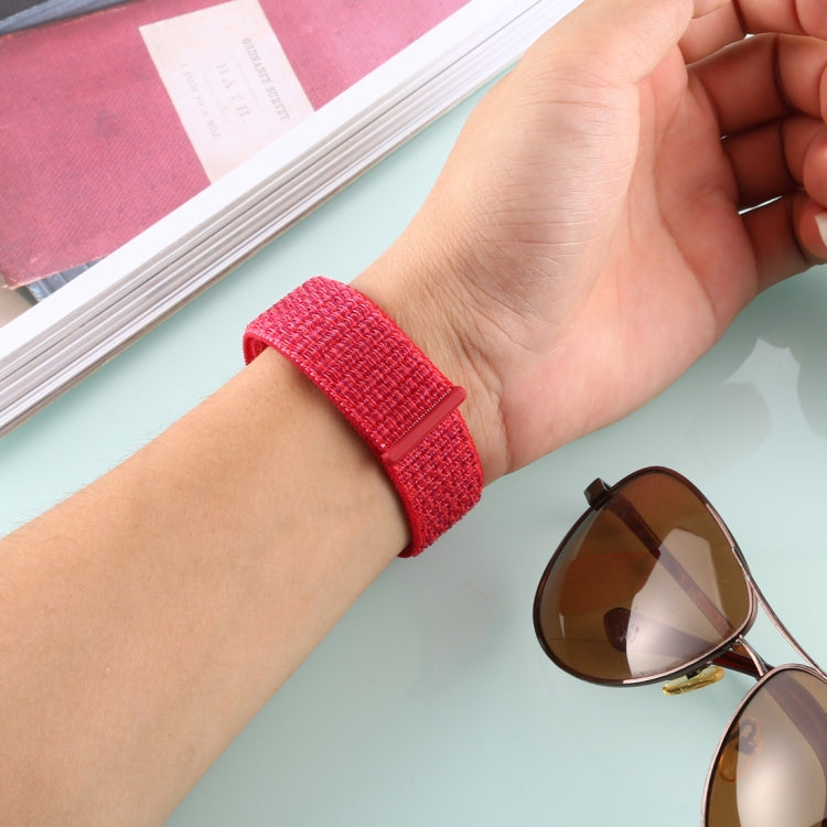 Red nylon watch band with hook-and-loop closure worn on wrist