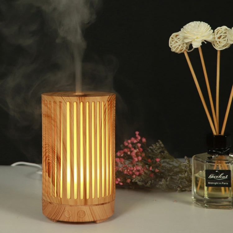 Wooden essential oil humidifier with vertical slot cutouts, amber LED glow, mist vapor