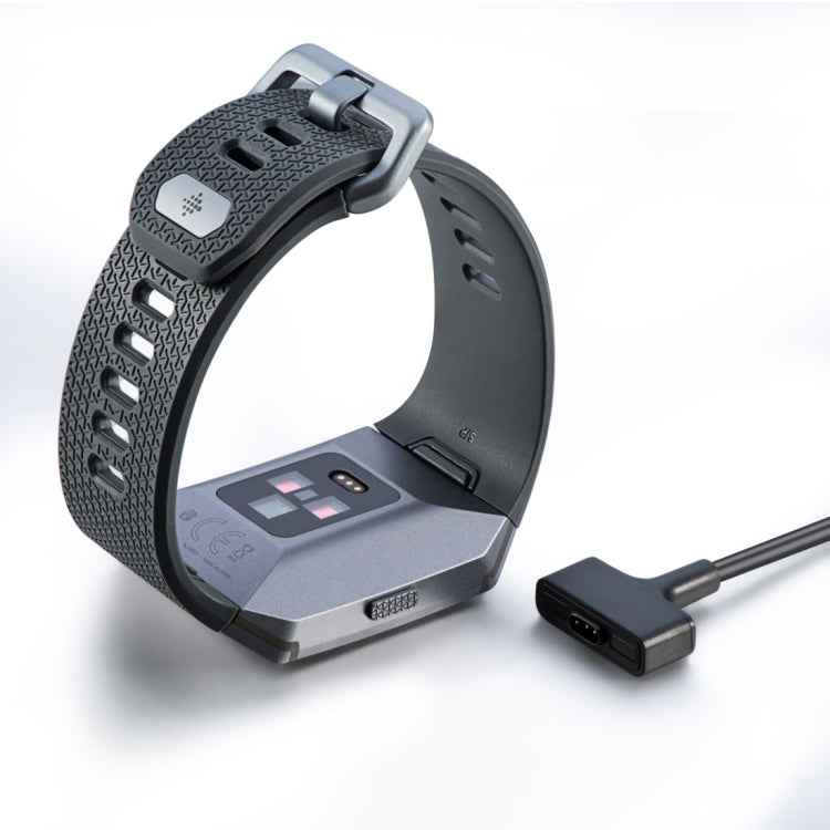 Charging cable plugged into a smartwatch dock, black band and cable end