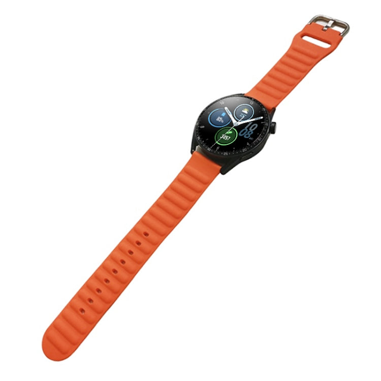 Orange silicone watch band on smartwatch, ridged strap with metal pin buckle.