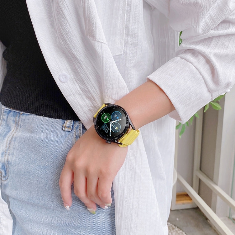 Yellow silicone watch band on a smartwatch, ridged strap with metal pin buckle.