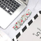 Floral cloth watch band, white with red flowers and green leaves; laid flat for view.