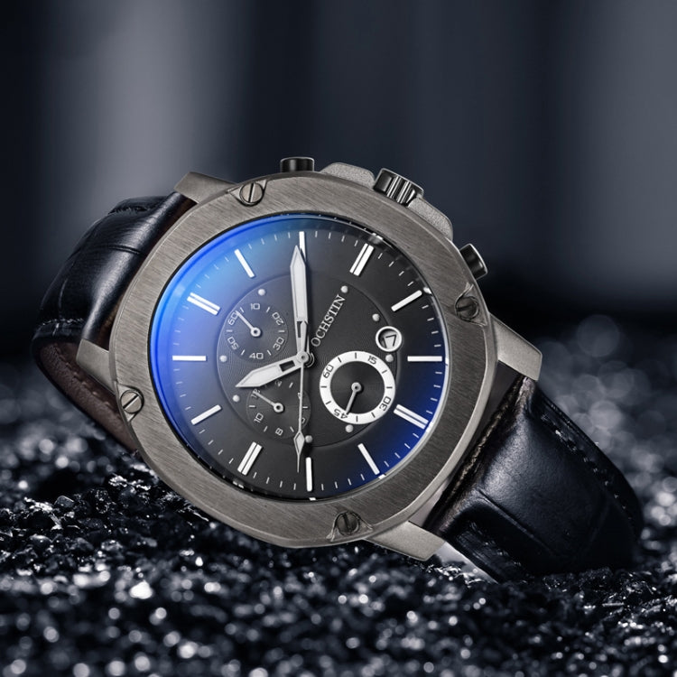 Men's multifunction watch close-up with black leather strap, dark dial, blue luminous-style highlights.