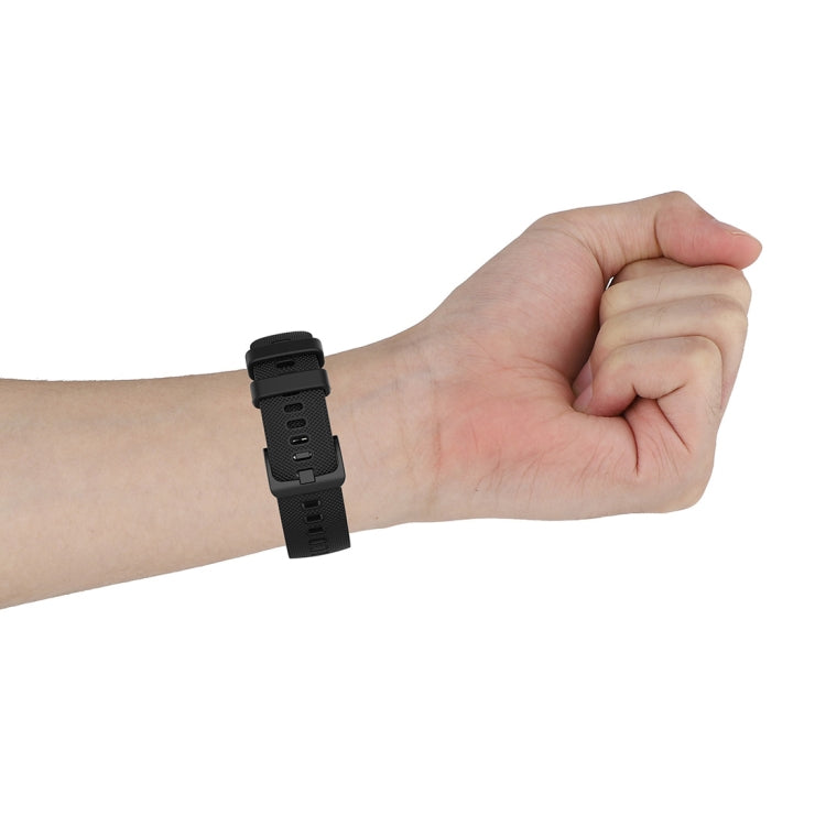 Black silicone watch strap with small plaid texture worn on wrist, buckle visible