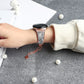 Rose gold rhinestone watch band on wrist with metal chain and clover charm