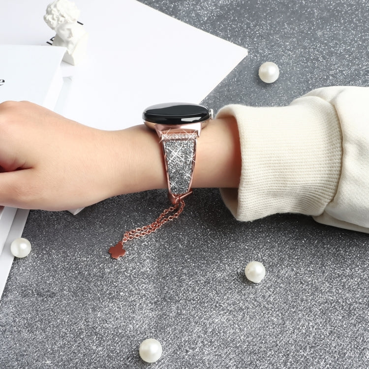Rose gold rhinestone watch band on wrist with metal chain and clover charm