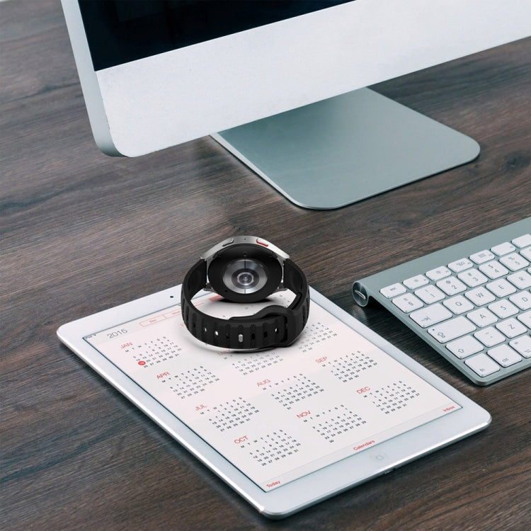 Black silicone watch band with dot-texture strap and pin holes, laid flat on desk