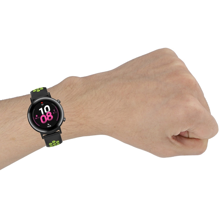 Silicone sports watch strap, black with green perforated pattern worn on wrist