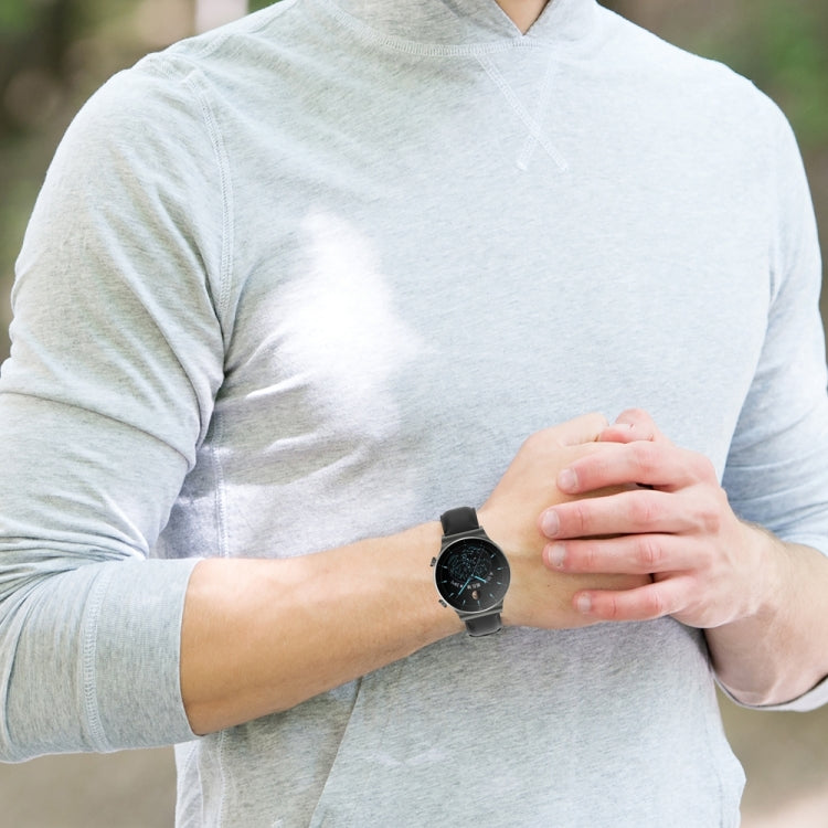 Round smartwatch on wrist with black leather watch band and metal clasp
