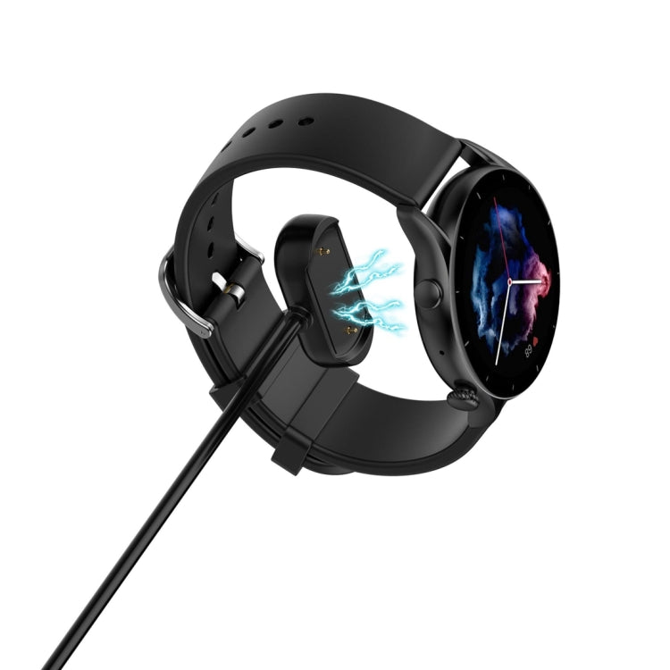 Magnetic charging cable connected to a black smartwatch, charging dock visible