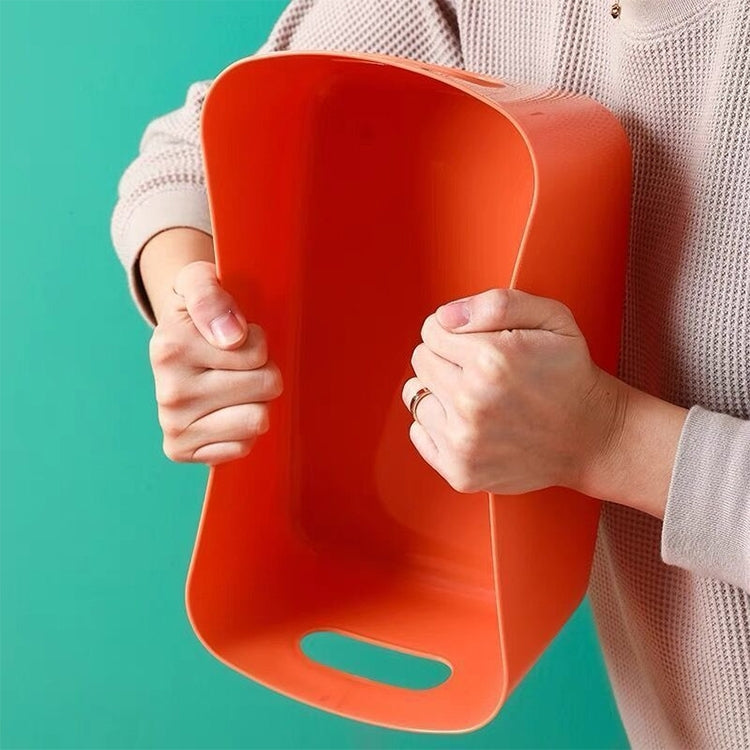 Orange plastic snack storage basket with side handle cutout, held in hands