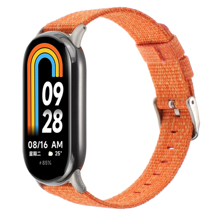Orange nylon canvas watch band with metal clasp and pin buckle for a fitness tracker.