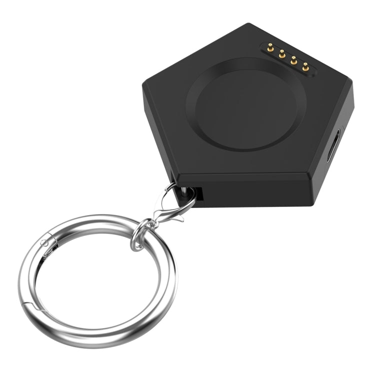 Black keychain smartwatch charger showing its charging surface and four gold contacts
