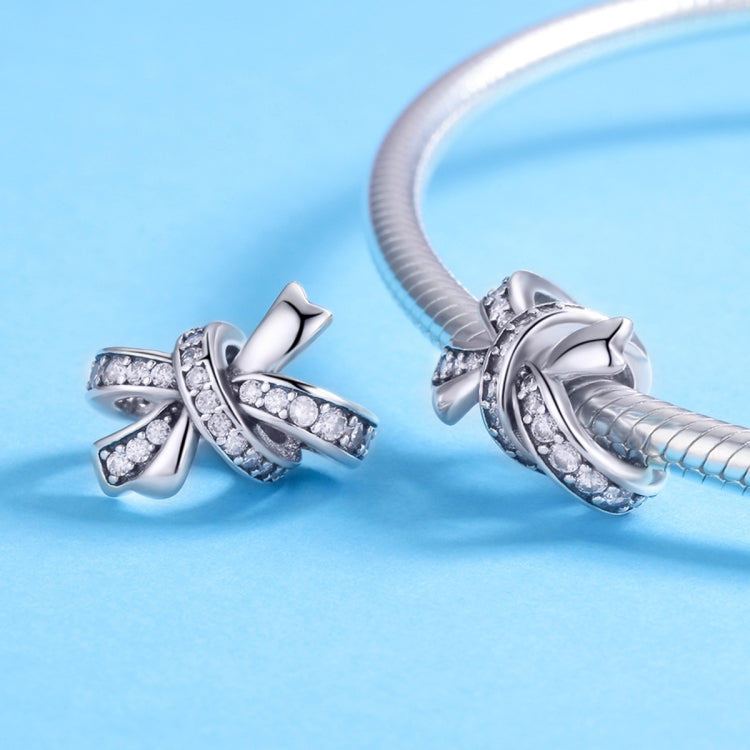Sterling silver bow bead charm with clear stones, shown loose and on a bracelet