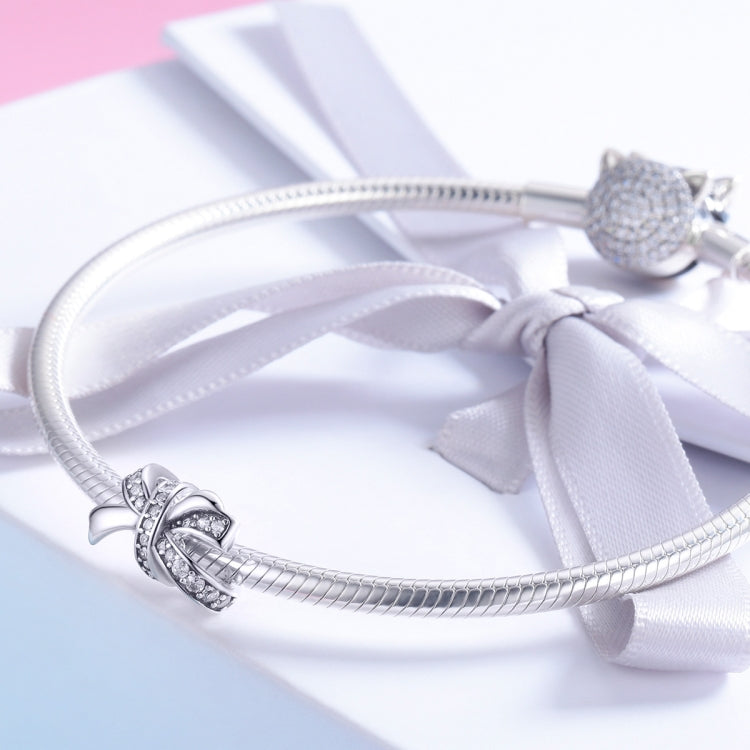 Sterling silver bow knot charm on a snake chain with a white ribbon accent