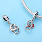 Two silver heart charms on bracelet, one with red enamel and stone border