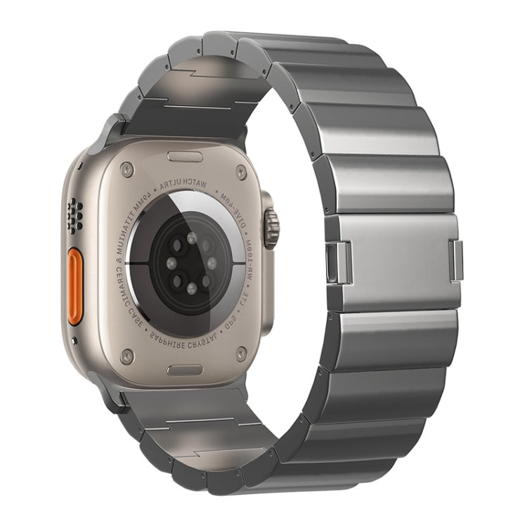 Dark metal watch band with broad links, shown with the watch back and orange side button.