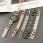 Metal chain watch bands in gold, rose gold, silver, black, and dark gray; one is fitted to a round watch.
