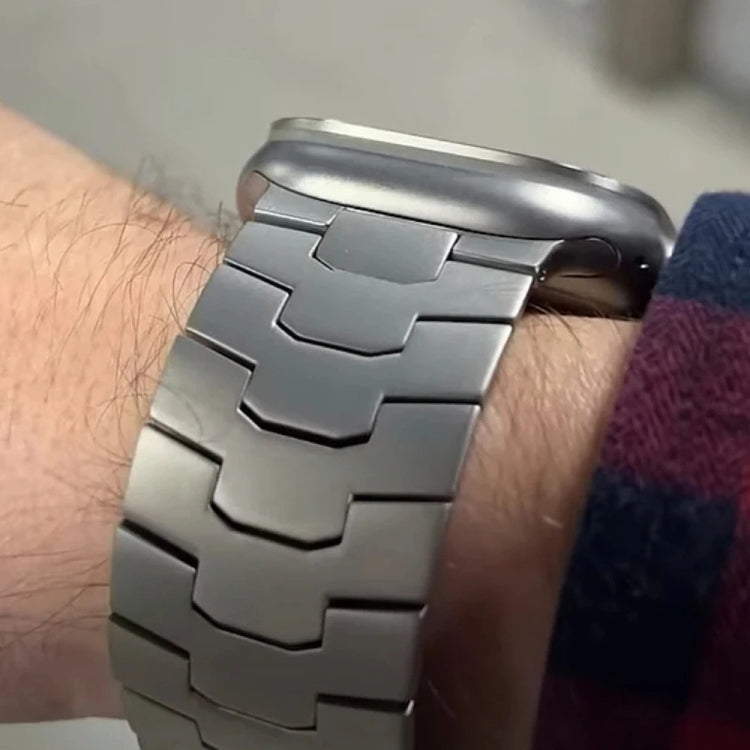 Titanium alloy Apple Watch band with broad interlocking links, worn on a wrist