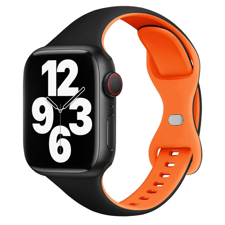 Two-tone silicone watch band in black and orange with butterfly buckle, shown on a smartwatch.