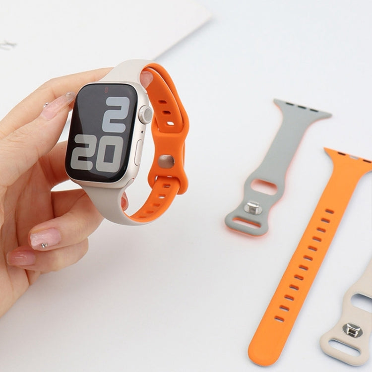 Orange and light gray silicone watch band parts beside a smartwatch