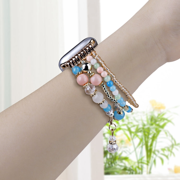 Multicolor beaded Apple Watch band worn on wrist, with dangling crystal charm